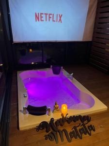 a purple bath tub with a candle and a tv at Tiny House Bungalow - Pool, Jacuzzi, Winter Garden in İzmir