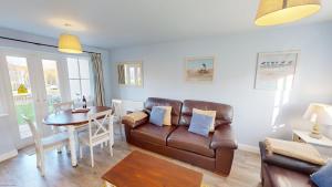 a living room with a leather couch and a table at Willow Cottage - Part of the The Bay Filey Holiday Village with pool, gym and direct beach access, pub, restaurant, tennis and meadows walks in Reighton