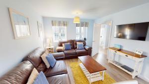 a living room with a leather couch and a table at Willow Cottage - Part of the The Bay Filey Holiday Village with pool, gym and direct beach access, pub, restaurant, tennis and meadows walks in Reighton
