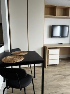 Cette chambre comprend une table et des chaises noires ainsi qu'une télévision. dans l'établissement Delta Apart-House, à Wrocław