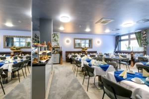 un restaurant avec des tables et des chaises bleues et blanches dans l'établissement Hotel Rivoli, à Munich