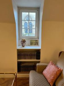 um quarto com uma janela, uma cadeira e livros em Tea Time em Douvres-la-Délivrande