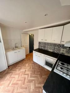uma cozinha com armários brancos e piso em madeira em Tea Time em Douvres-la-Délivrande