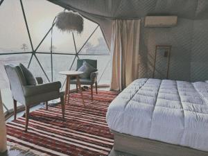 a bedroom with a bed and chairs and a large window at Ciel D'Etoile Sahara in Merzouga