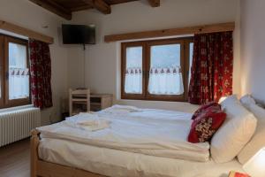 a large bed in a room with two windows at ALLE ANTICHE MINIERE - CASA VACANZE in Zenich