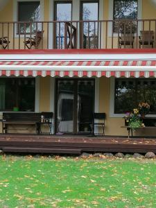 une maison avec une terrasse couverte et un banc devant elle dans l'établissement Villa River Rose, à Jõesuu