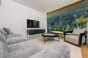 a living room with a couch and a large window at Luxury architecture chalet with view and wellness in Bludenz