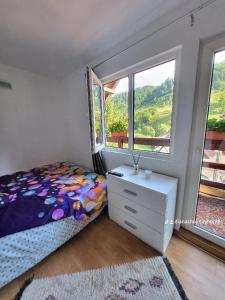 ein Schlafzimmer mit einem Bett, einer Kommode und einem Fenster in der Unterkunft Diana's Holiday Home in Podu Dîmboviţei