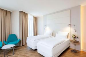 a hotel room with two beds and a blue chair at NH Berlin Alexanderplatz in Berlin