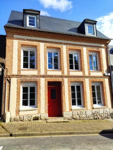 a brick house with a red door on a street at Gîte de l'église à Saint Saëns in Saint-Saëns