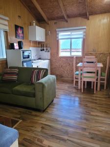 a living room with a green couch and a table at Cabañas Vientos del Sur en Puerto Puyuhuapi Aysen in Puerto Puyuhuapi