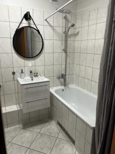 a bathroom with a tub and a sink and a mirror at Delta Apart-House in Wrocław