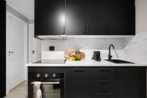 a kitchen with black cabinets and a cutting board with fruit at King bed - Renovated 2024 - 2BR Behind Bryggen in Bergen