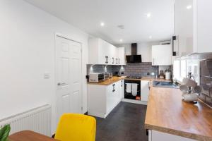 a kitchen with white cabinets and a yellow chair at Stylish 3 bed Edinburgh Abode - Parking and Garden in Edinburgh