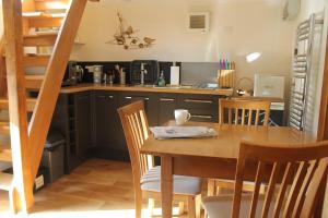 a kitchen and dining room with a wooden table and chairs at The Hide at Lemons Farm in Atherington +10 photos