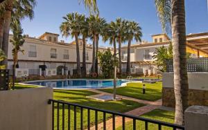 un complexe avec une piscine et des palmiers dans l'établissement Adosado con jardin y piscina Palm Beach 86 ALBERT VILLAS, à Alcossebre
