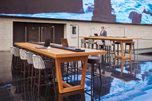 a man in a room with tables and chairs with laptops at Hyatt Regency Barcelona Tower in Hospitalet de Llobregat