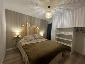 a bedroom with a large bed and a chandelier at Belle villa avec spa et sauna in Tayrac +30 photos