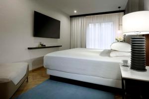 een slaapkamer met een groot wit bed en een televisie bij Hyatt Regency Hesperia Madrid in Madrid