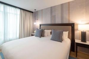 a bedroom with a large white bed with blue pillows at Hyatt Regency Hesperia Madrid in Madrid