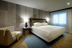 um quarto com uma grande cama branca e uma cadeira em Hyatt Regency Hesperia Madrid em Madri