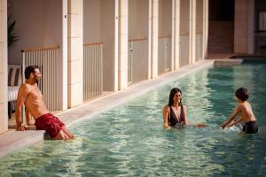 un hombre y dos niños jugando en una piscina en Anantara Vilamoura Algarve Resort, en Vilamoura