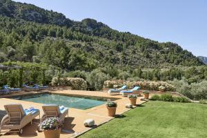 Villa Can Miquelet Deia في دِيّا: حديقه خلفيه بها مسبح وكراسي والجبل