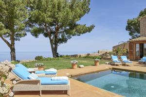Villa Can Miquelet Deia في دِيّا: حديقه خلفيه مع مسبح وكراسي صاله ومسبح