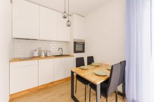 a kitchen with a wooden table and white cabinets at Apartament Berlinek in Grzybowo +6 photos