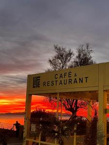 een bord voor een levend restaurant met de zonsondergang op de achtergrond bij Life House B&B in Follonica