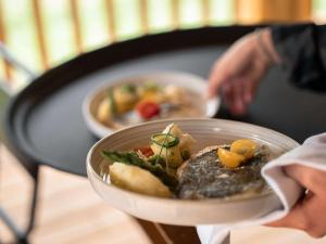 a person holding a bowl of food on a table at Mercure Peyragudes Loudenvielle Pyrénées in Loudenvielle