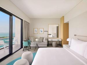 a bedroom with a bed and a room with a view at Mövenpick Resort Al Marjan Island in Ras al Khaimah