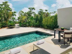 a swimming pool in a backyard with a table and chairs at Mövenpick Resort Al Marjan Island in Ras al Khaimah