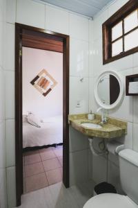 a bathroom with a sink and a mirror and a bed at Hostel Cabo Frio in Cabo Frio