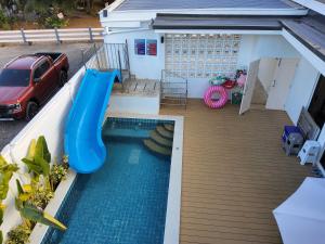 a swimming pool with a slide in a backyard at อิมอิม เฮ้าส์ พูลวิลล่า อุดรธานี in Udon Thani