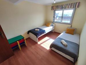 um pequeno quarto com 2 camas e uma janela em Oeiras, 2 bedroom apartment w balcony and barbecue next to Parque dos Poetas em Oeiras