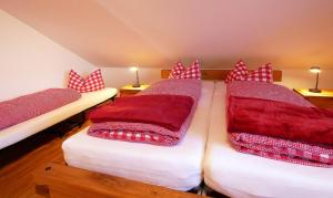 two beds in a room with red and white pillows at Ferienwohnungen beim Sommermader in Nesselwang