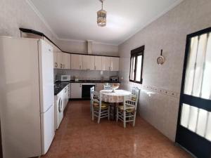 een keuken met een tafel en een witte koelkast bij Vivienda rural Los Iberos M&M in Castellar de Santisteban