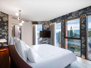 a bedroom with a large white bed and large windows at Swissôtel Tbilisi in Tbilisi City