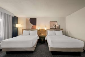 two beds in a hotel room with white sheets at Spark By Hilton Fort Wayne in Fort Wayne