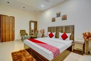 a bedroom with a large bed with red pillows at Flagship Hotel Orchid in Ludhiana