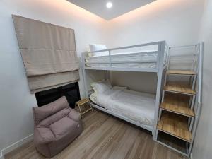 a room with two bunk beds and a chair at อิมอิม เฮ้าส์ พูลวิลล่า อุดรธานี in Udon Thani