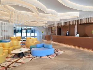 een lobby met blauwe stoelen en tafels en een plafond bij Mövenpick Hotel & Apartments Ghala Muscat in Muscat
