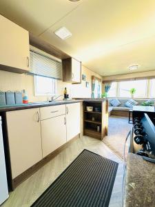 a kitchen with white cabinets and a living room at Dunlin Retreat in Flamborough