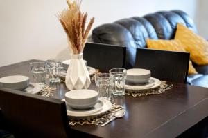 einen Tisch mit Tellern, Gläsern und einer Vase in der Unterkunft Open Mind Property - Luxury Apartment Near Hospital & Underground Free Parking for 2 Vehicles in Southampton