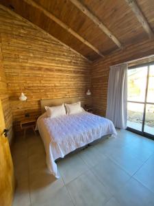 1 dormitorio con 1 cama y pared de madera en Balcon del Golf en Sierra de la Ventana