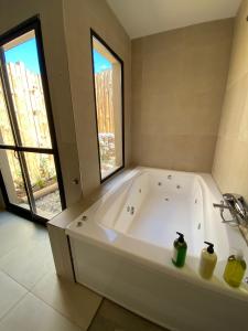 a large white tub in a bathroom with two windows at Balcon del Golf in Sierra de la Ventana