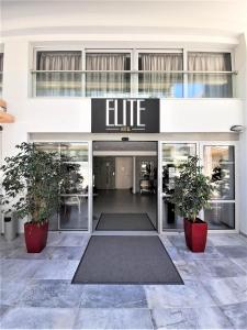 ein Gebäude mit zwei Topfpflanzen davor in der Unterkunft Elite Hotel in Rhodos (Stadt)