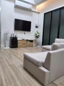 sala de estar con sofá y TV de pantalla plana en อิมอิม เฮ้าส์ พูลวิลล่า อุดรธานี, en Udon Thani