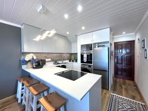eine Küche mit weißen Schränken und einem blauen Kühlschrank in der Unterkunft Coastal Hospitality - De Valle 65 in Mossel Bay